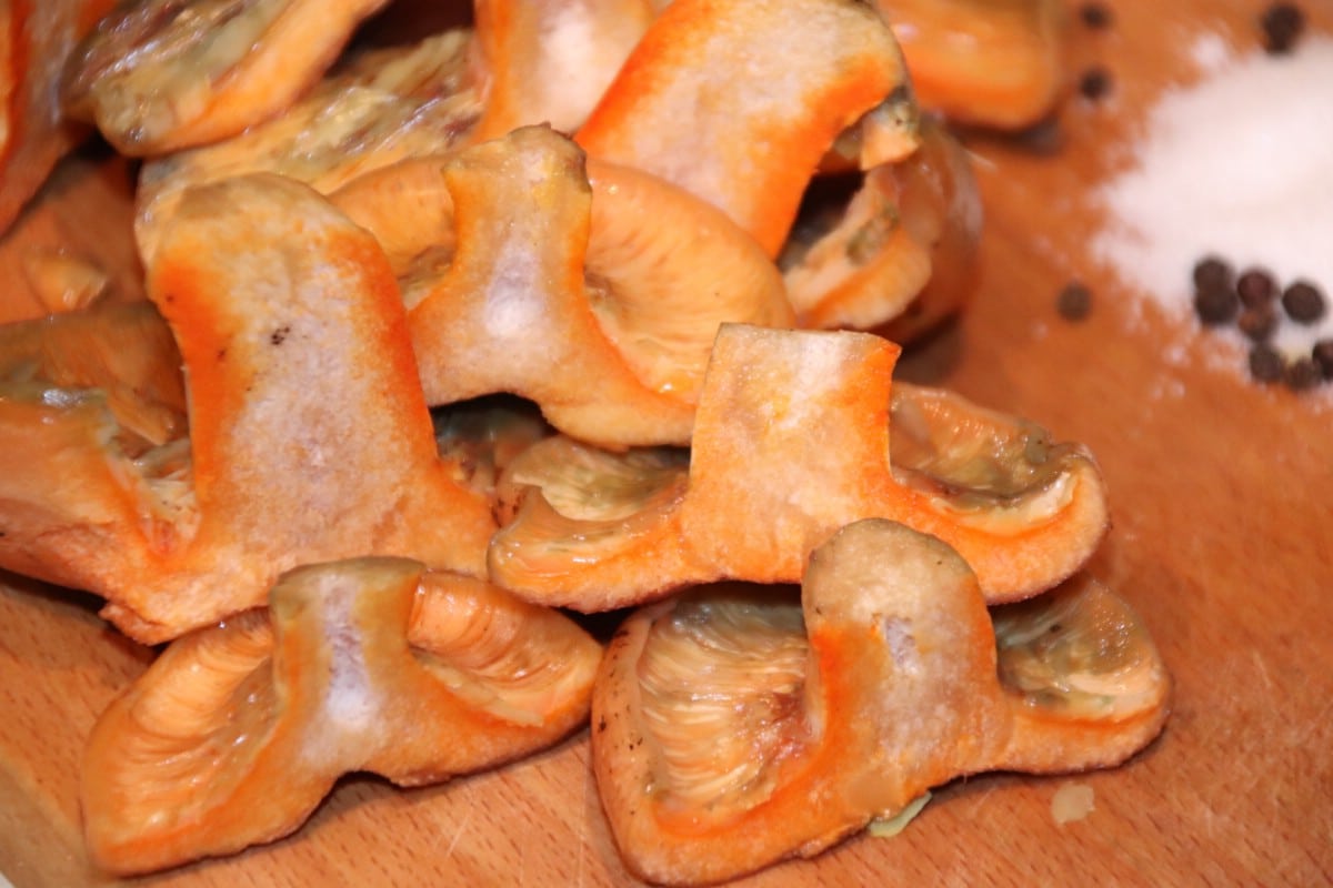 Halved saffron milk caps on a cutting board.